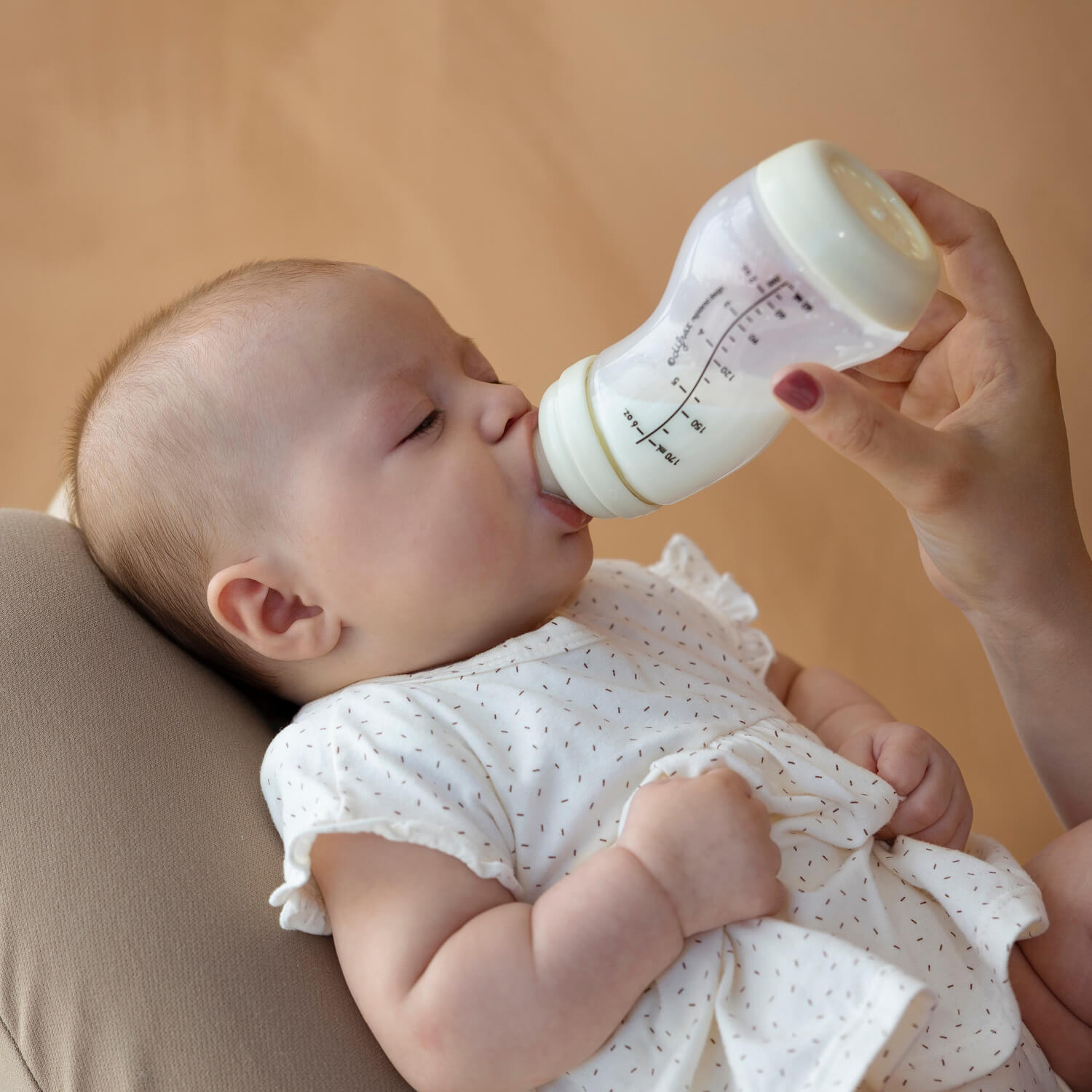 Pasgeboren baby drinkt uit Difrax S-flesje 170ml ivory, gevuld met moedermelk