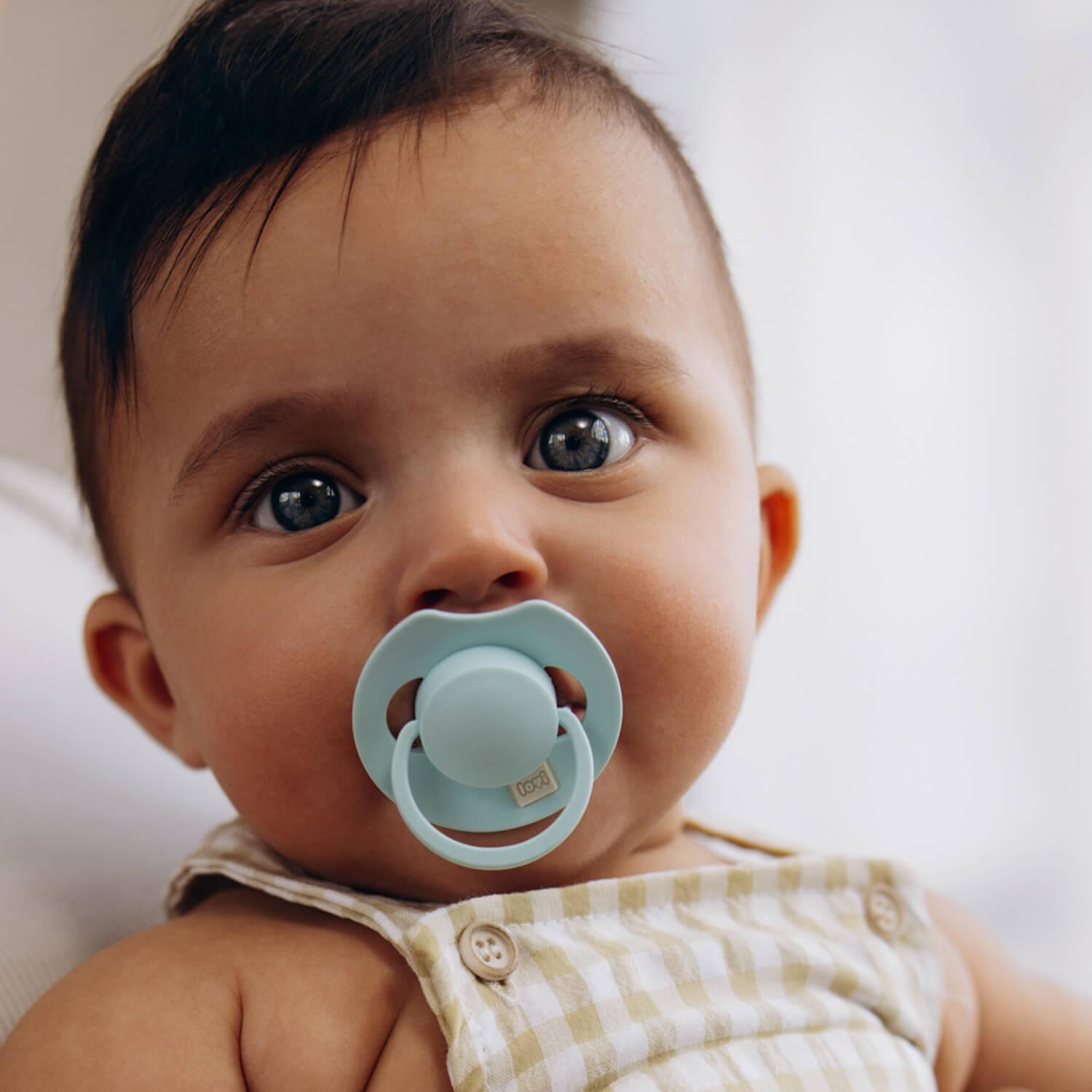 Donkerharige baby met een aqua LOVI Dynamic fopspeen (Tutti Frutti, Lagoon)