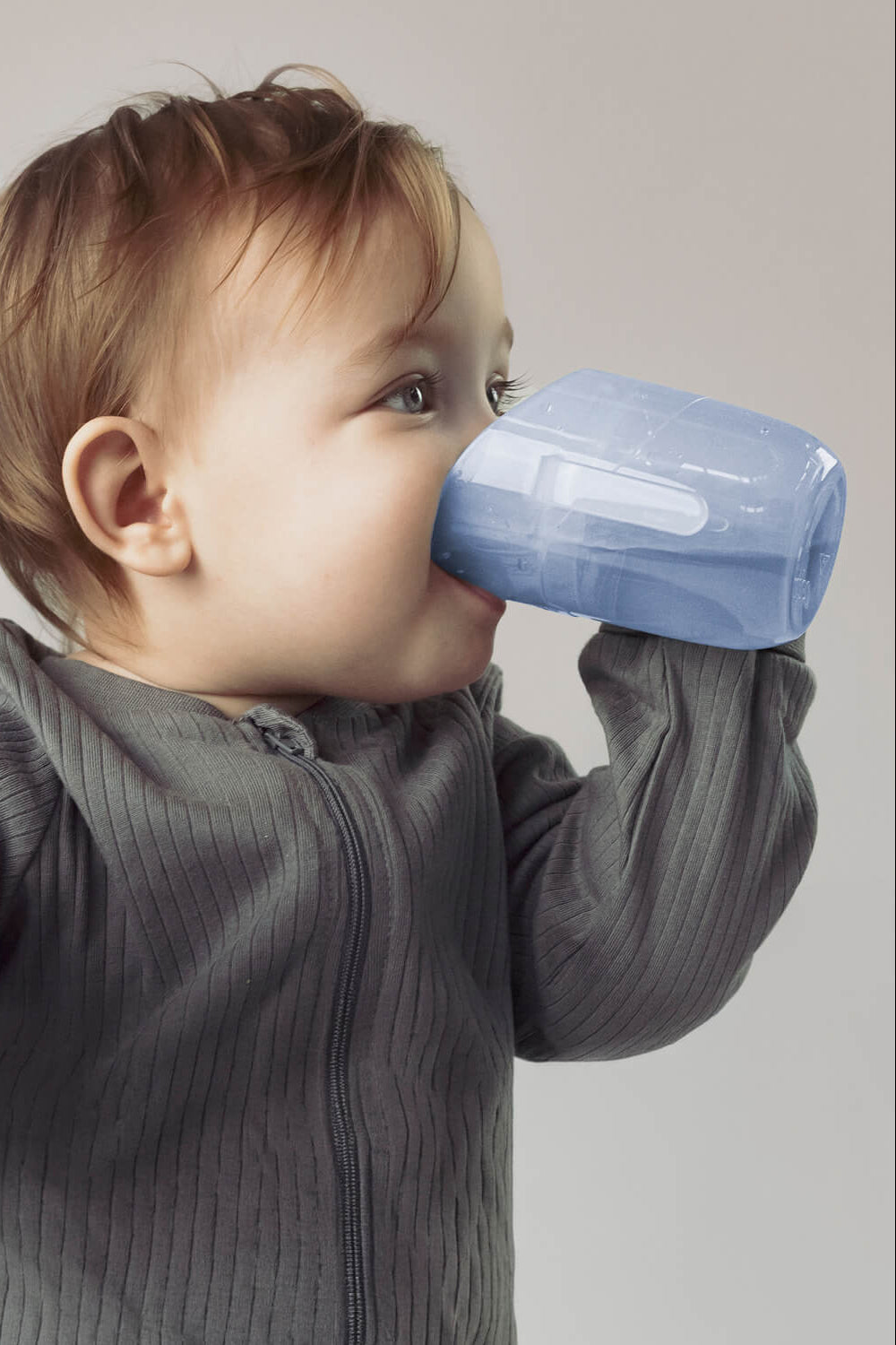 Baby drinkt uit een aquamarijn transparante Béaba Genius trainer cup met beide handjes