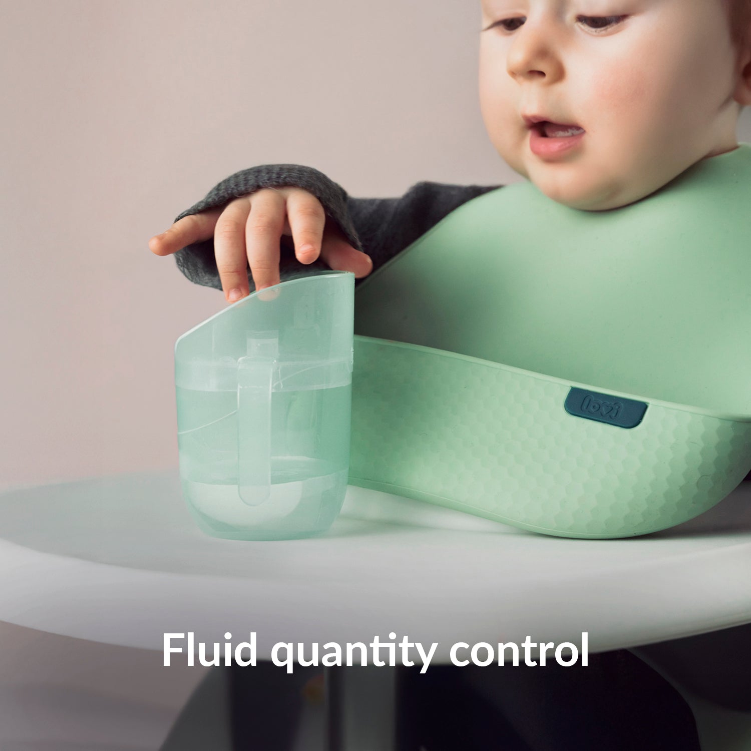 Kind aan eettafel met Difrax LOVI Genius oefenbeker, toont de functie voor vloeistofhoeveelheidscontrole