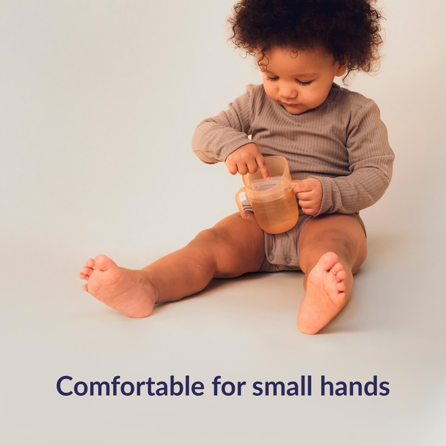 Peutermeisje zit op de grond en houdt de Difrax LOVI Genius oefenbeker vast – comfortabel en makkelijk vast te houden voor kleine handjes