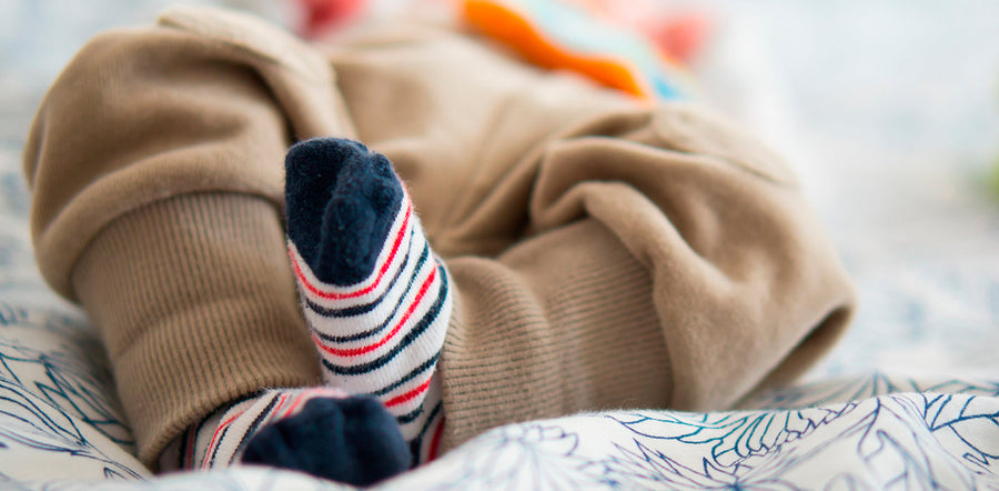 Un bébé porte des chaussettes aux pieds.