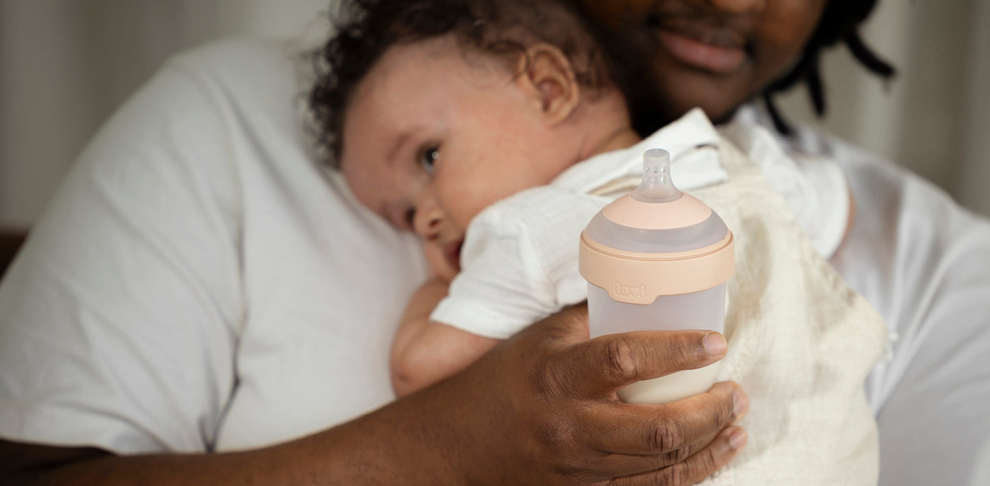 La sage-femme tient le bébé dans une main et un biberon Mammafeel dans l’autre