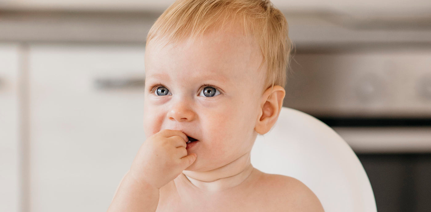 Le bébé met deux doigts dans la bouche, comme s’il mangeait