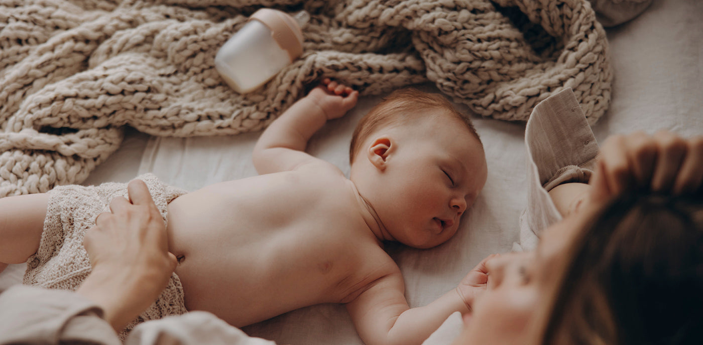 Le bébé dort près de sa mère, avec son biberon Mammafeel à côté de lui