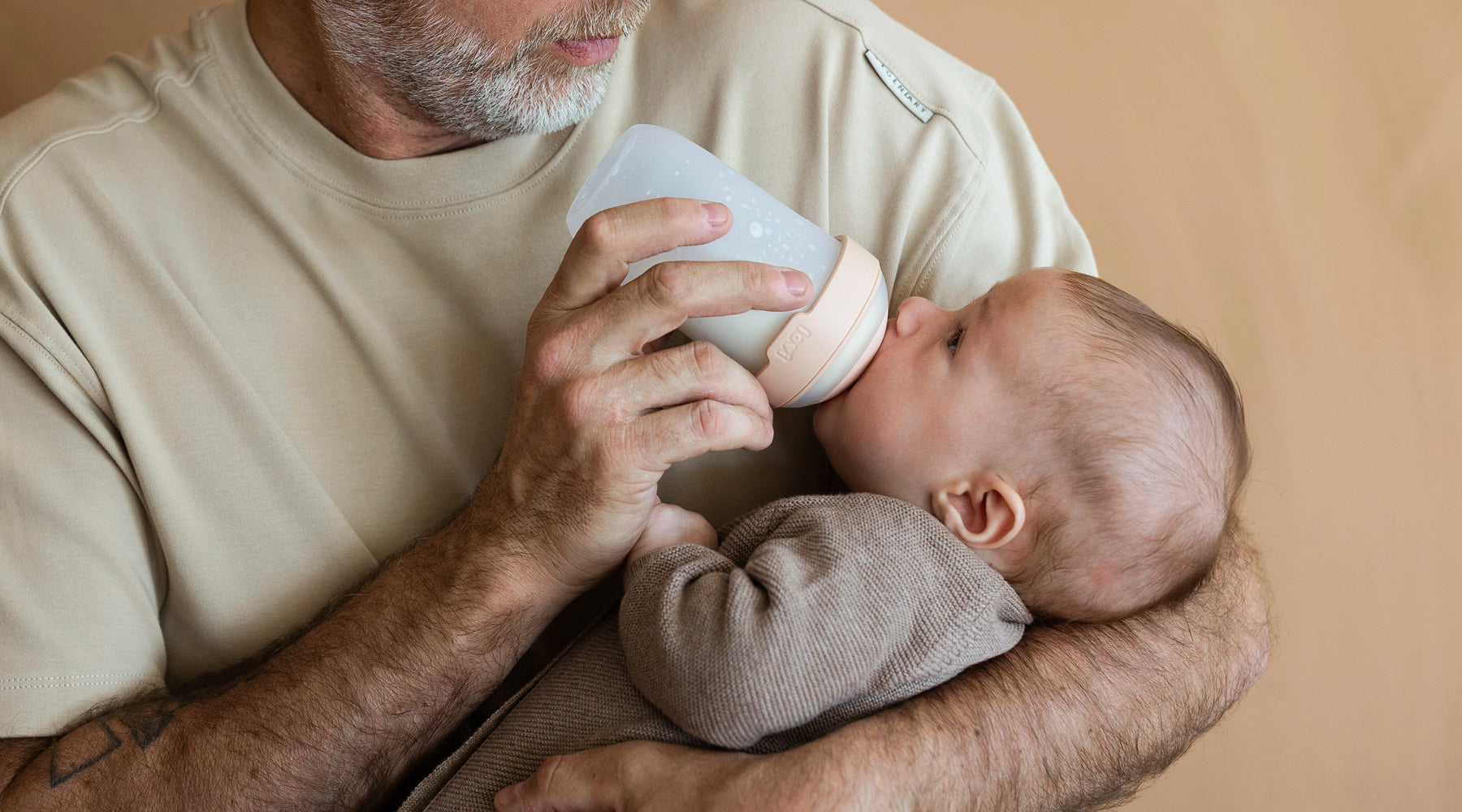 Père donnant le biberon Mammafeel à son bébé, biberon testé par les familles et noté 8,4 sur 10 pour sa douceur et facilité d’utilisation.