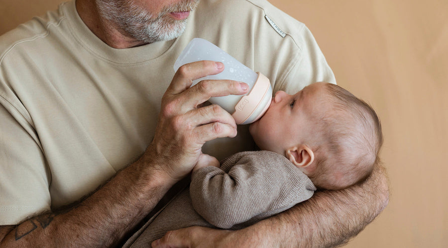 Père donnant le biberon Mammafeel à son bébé, biberon testé par les familles et noté 8,4 sur 10 pour sa douceur et facilité d’utilisation.
