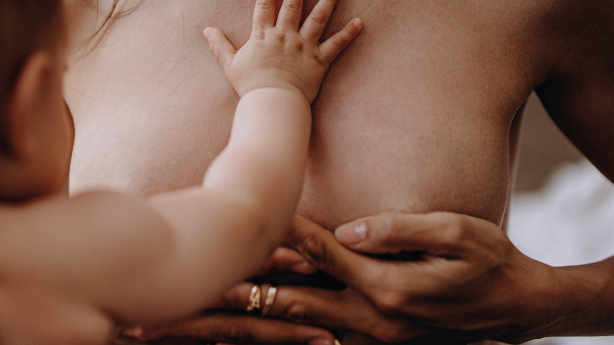 Moeder houdt haar borsten vast met baby 