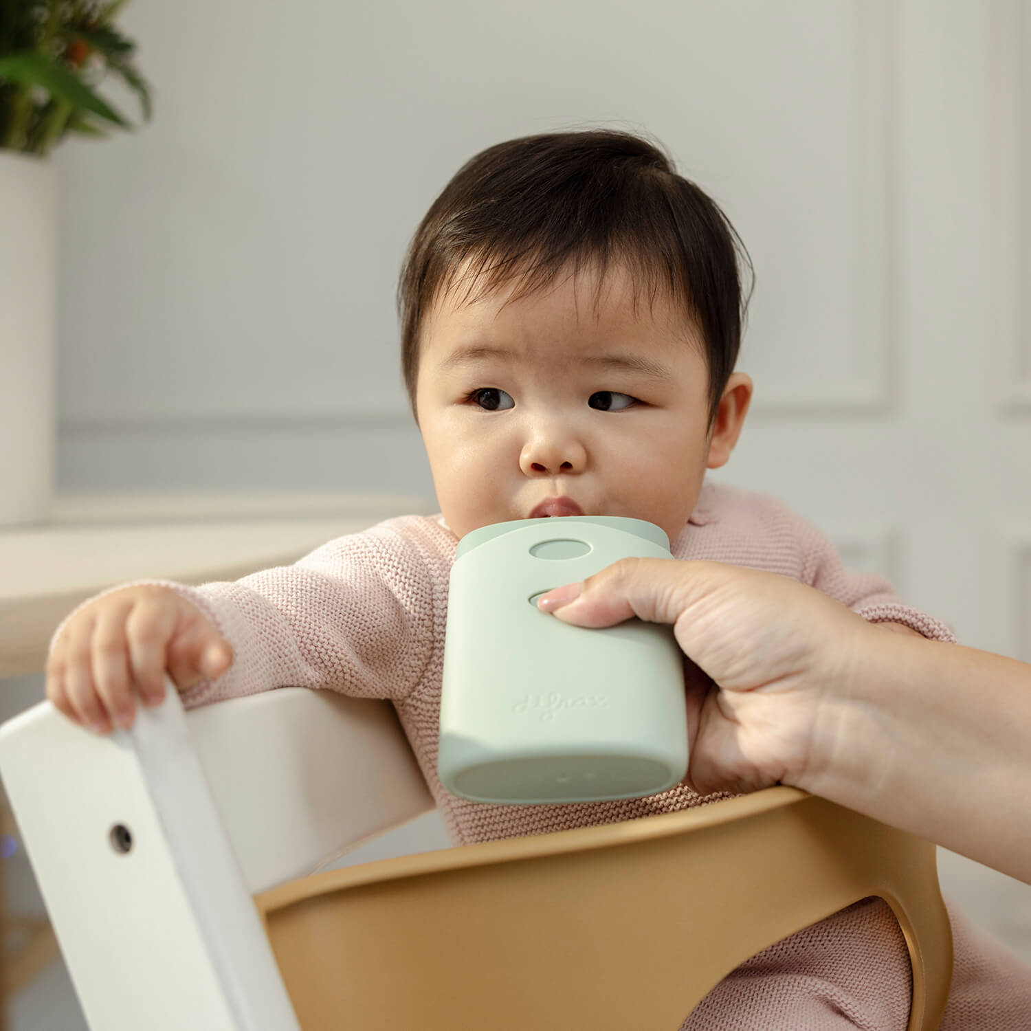 Peuter drinkt zelfstandig uit Difrax Pouchholder in kinderstoel, veilige en nette manier om knijpzakjes te gebruiken