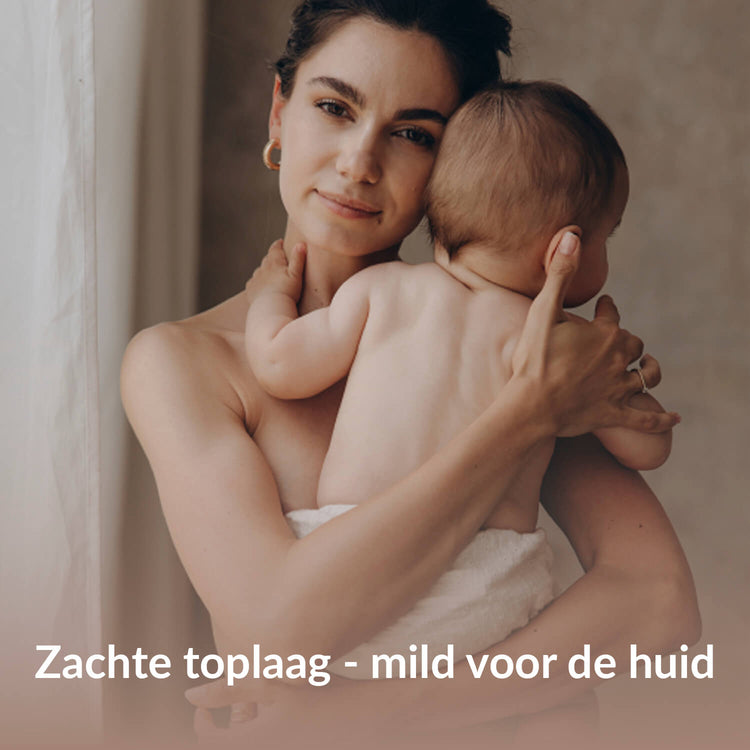 Moeder houdt een baby vast met een witte zachte onderlegger, met focus op een zachte toplaag.