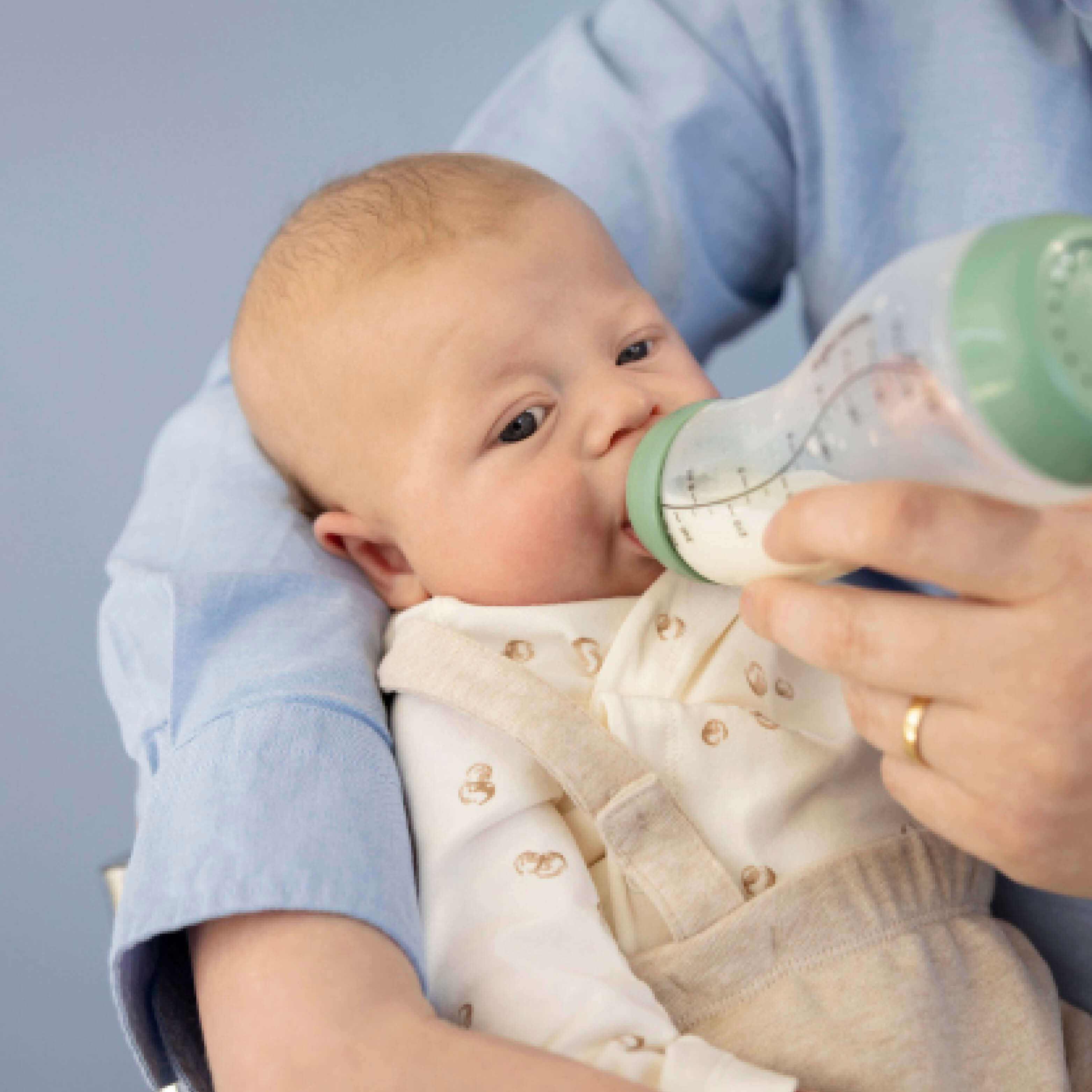 Pasgeboren baby wordt gevoed met Sage groene Difrax S-fles 250ml, intiem voedingsmoment in comfortabele positie