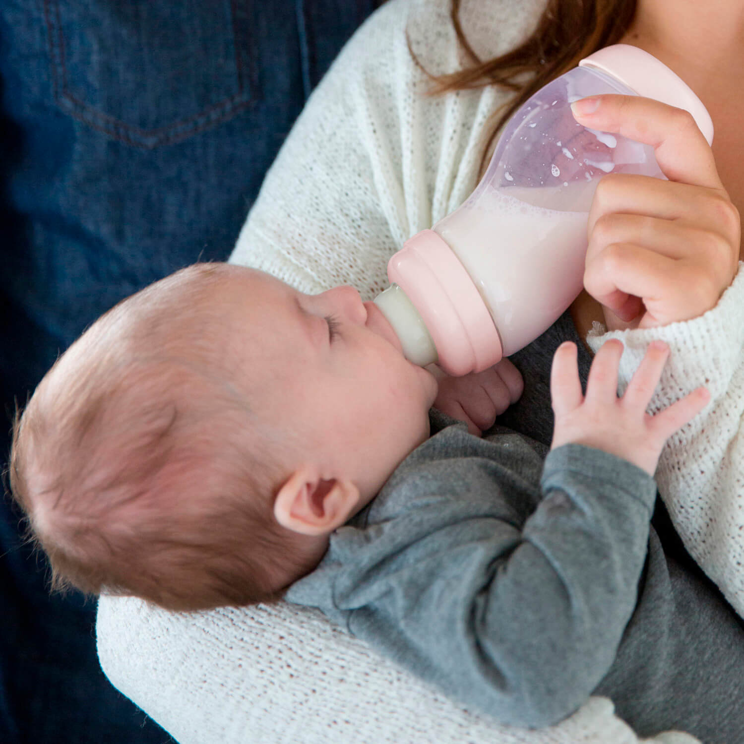 Baby wordt gevoed met roze Difrax S-fles 310ml, rustgevend voedingsmoment met moeder in comfortabele houding