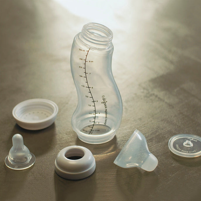 Difrax S-fles met mintgroene onderdelen naast gedemonteerde flesonderdelen inclusief speen, ring, en anti-colic inserts