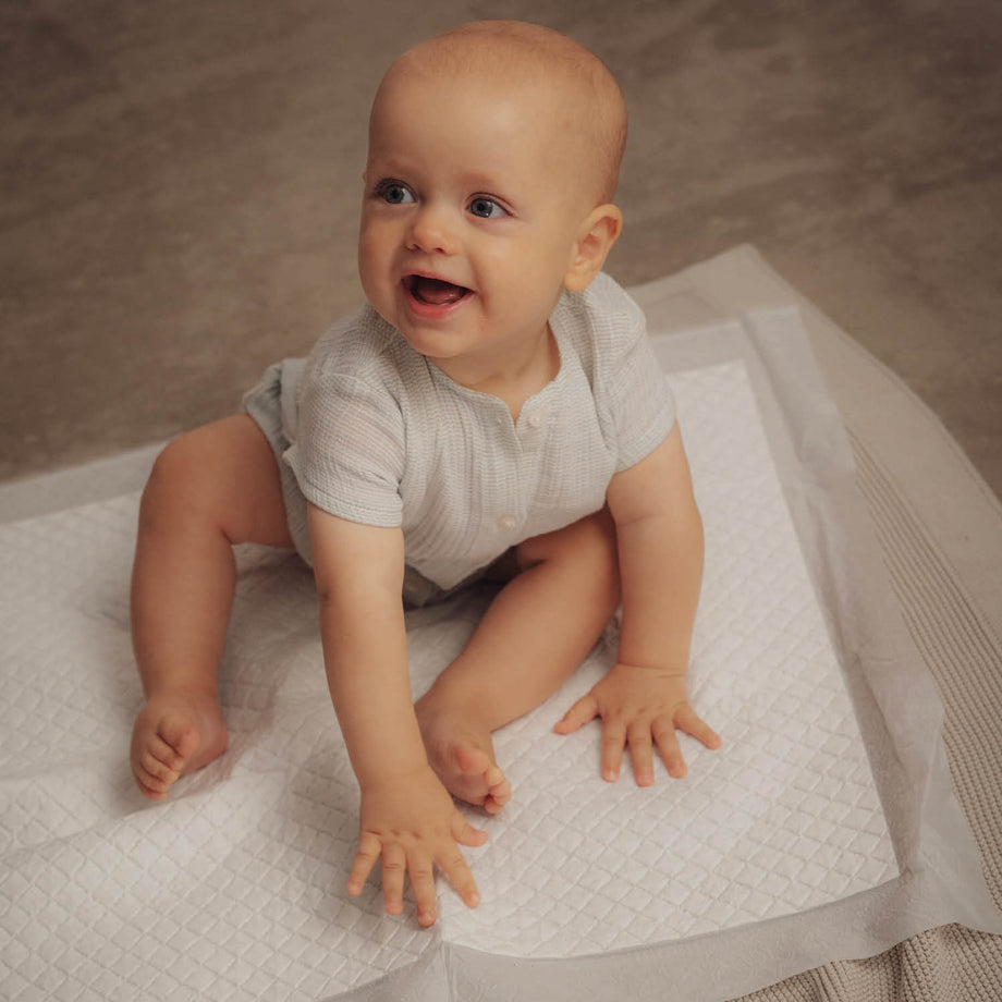 Baby zit op een witte wegwerp onderlegger