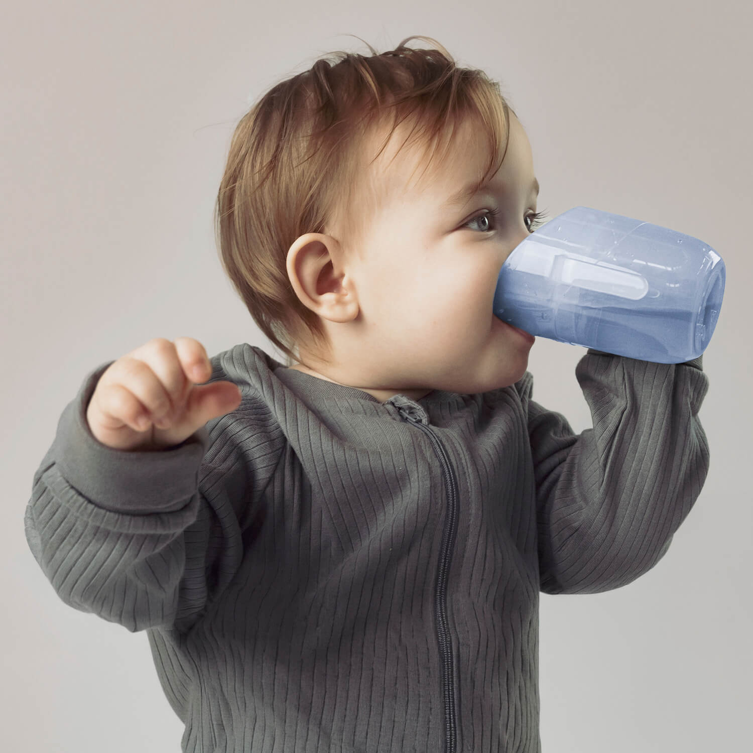 Baby drinkt uit een aquamarijn transparante Béaba Genius trainer cup met beide handjes