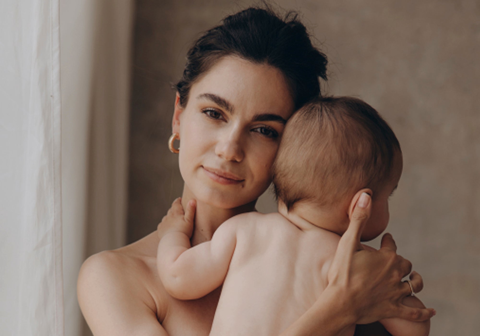 Moeder houdt pasgeboren kind hui dop huid vast. 