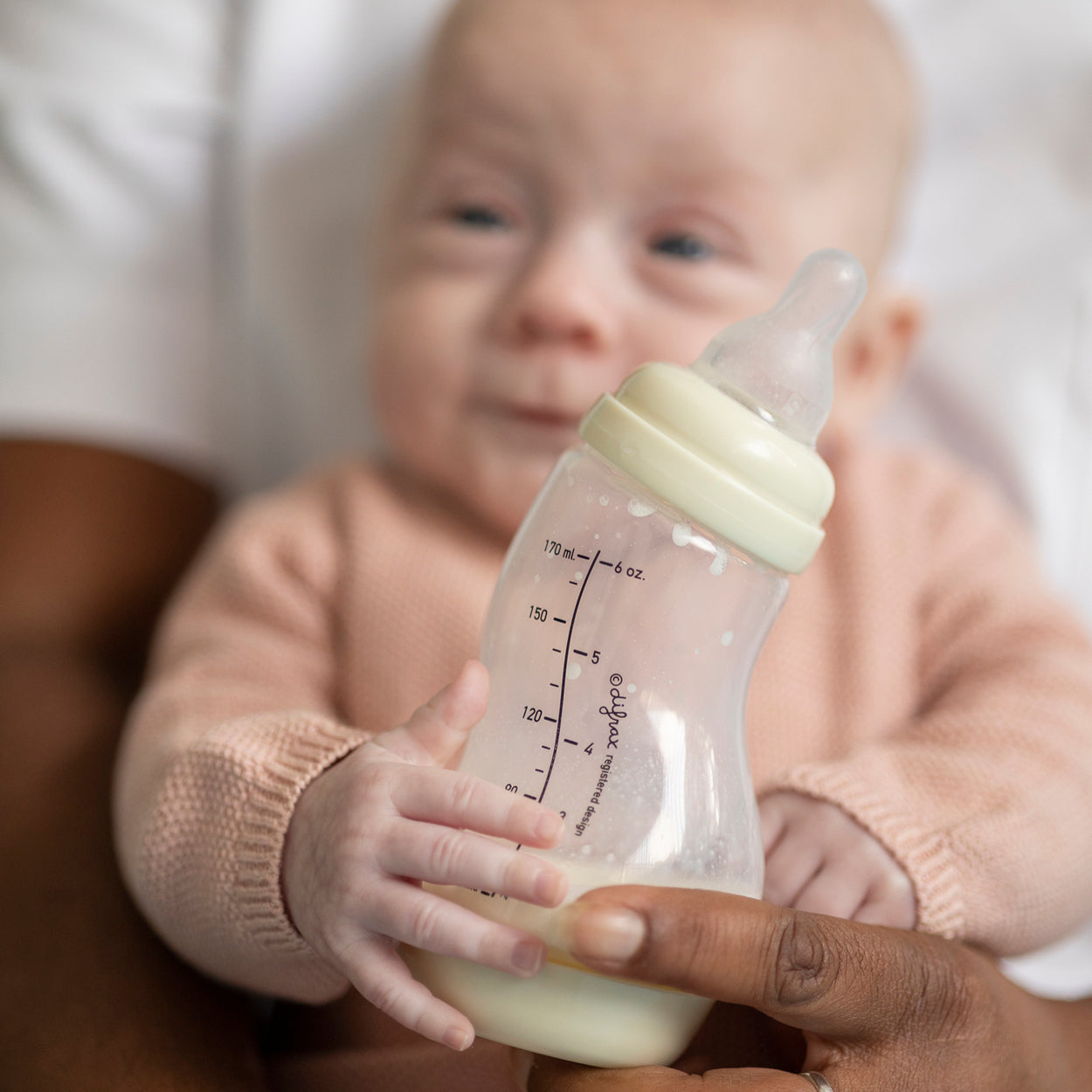 Pasgeboren baby krijgt flesvoeding samen met kraamzorg
