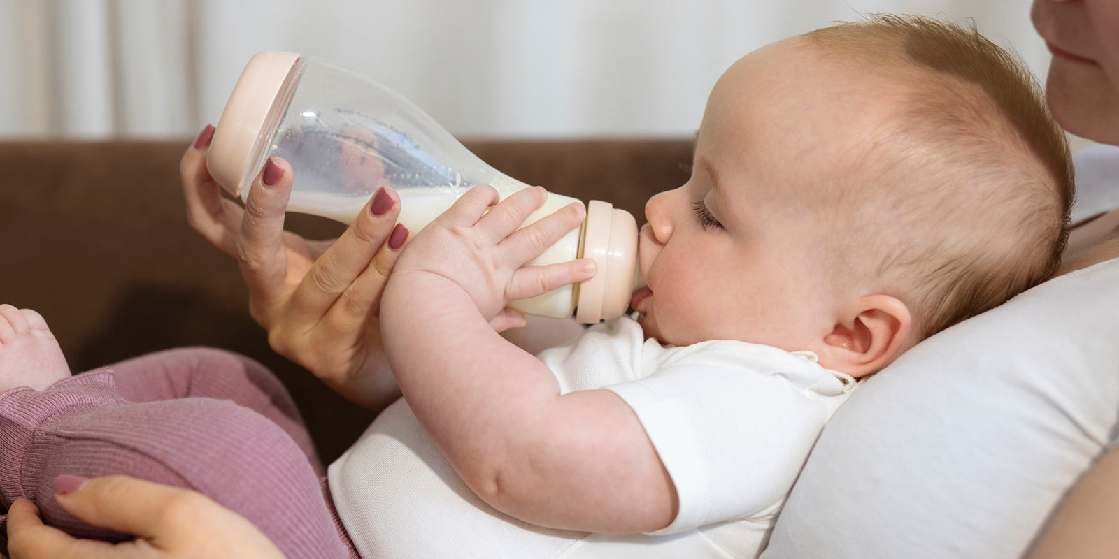 Baby ligt bij moeder en drinkt uit een Difrax glazen S-fles, veilig en duurzaam.