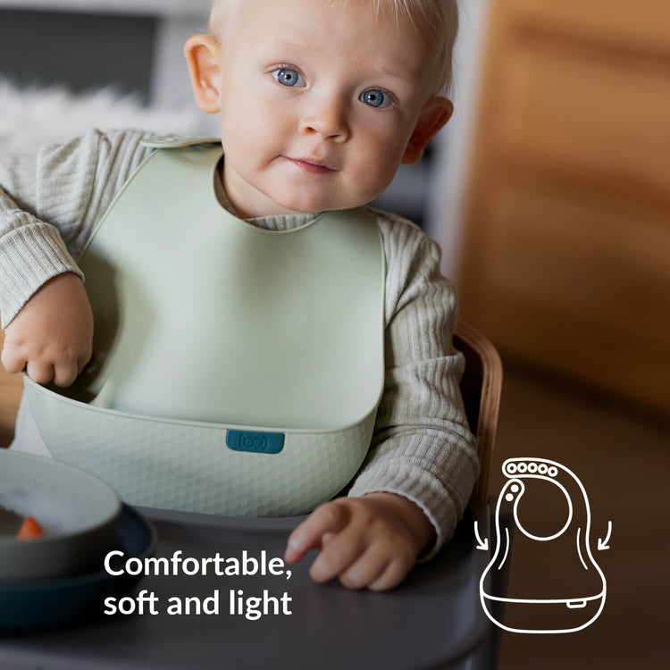Kind in kinderstoel met siliconen slab uit de Difrax LOVI Baby Eet- & Drinkset Pistachio – comfortabel, zacht en lichtgewicht tijdens het eetmoment.