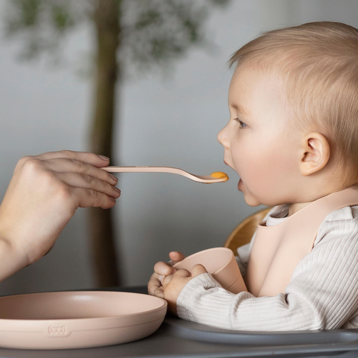 Baby wordt gevoed met een eerste voedingslepel in nudekleur