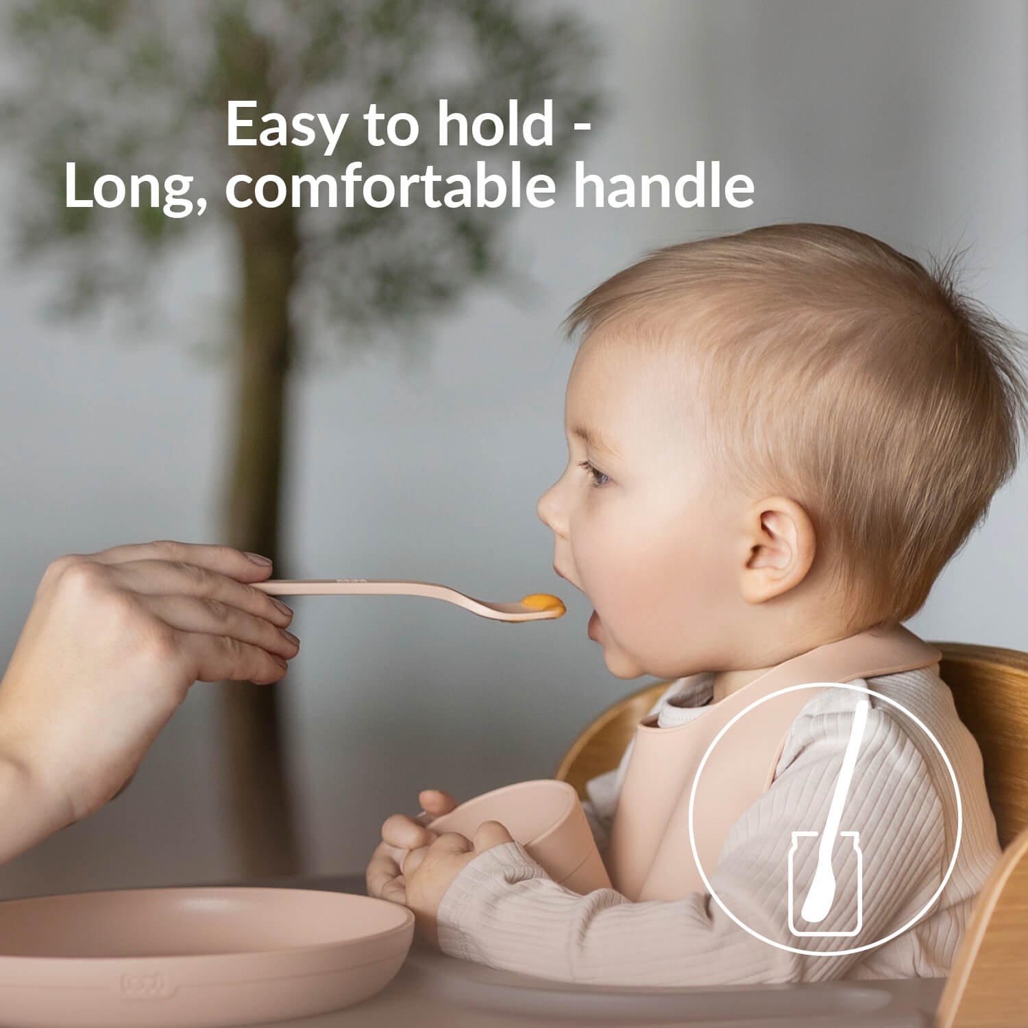 Baby wordt gevoed met een eerste voedingslepel in nudekleur met een lange en comfortabele steel