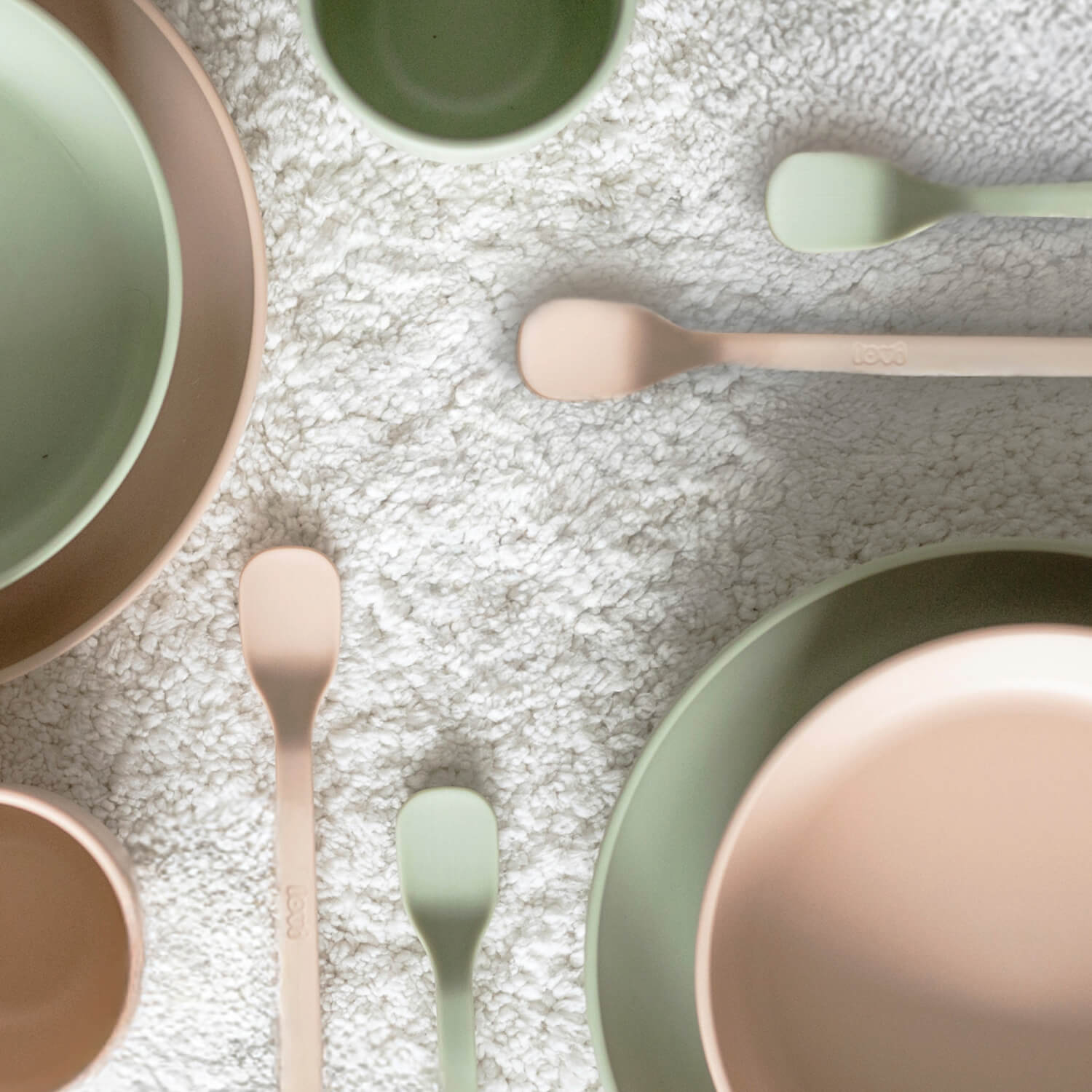 Sfeerbeeld van vier eerste voedingslepels voor baby’s in pistache- en nudekleur met bijpassende bakjes