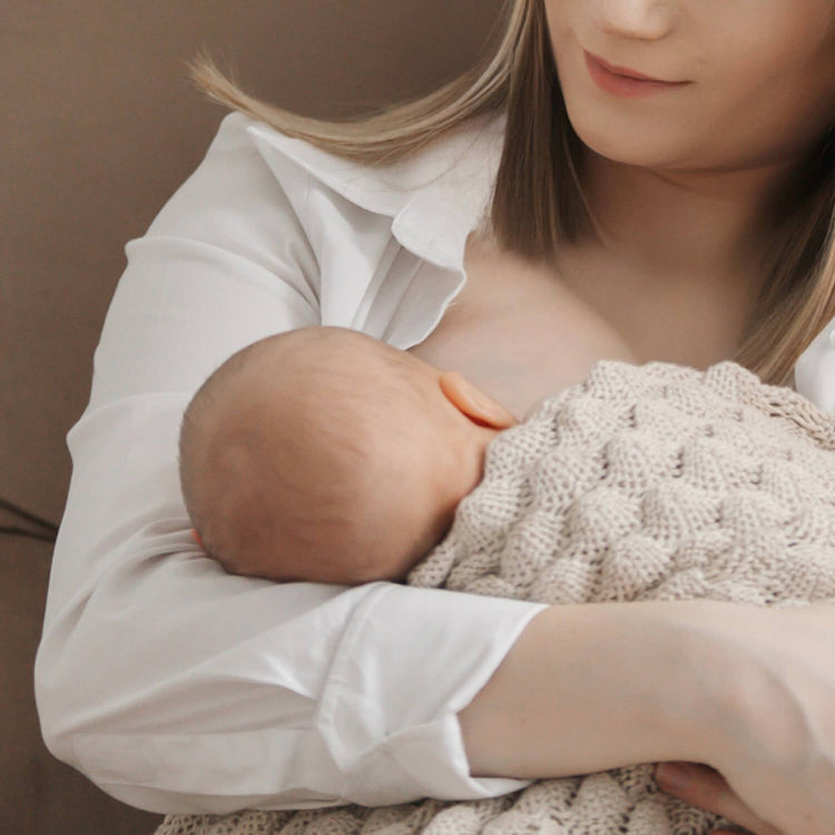 Moeder die haar baby borstvoeding geeft, met gebruik van zoogkompressen voor extra comfort

