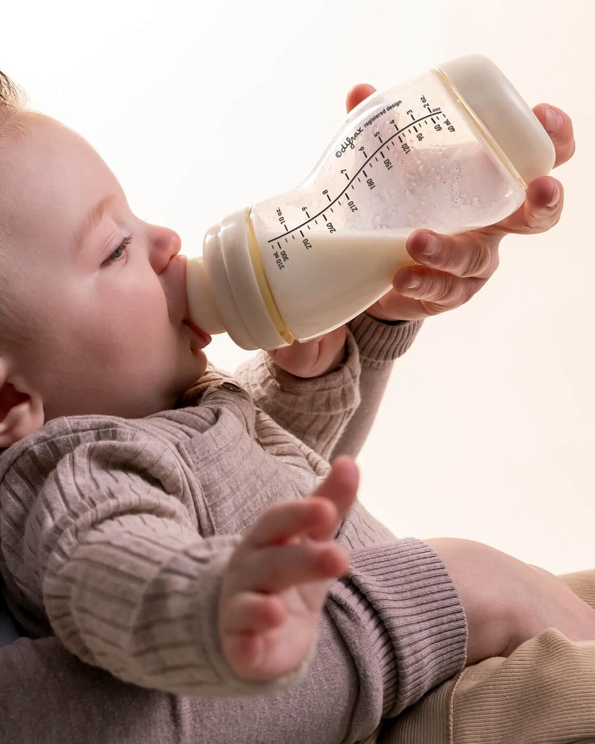 Peuter drinkt zelfstandig uit ivoorkleurige Difrax S-fles 310ml, ontwikkeling van onafhankelijkheid en zelfredzaamheid